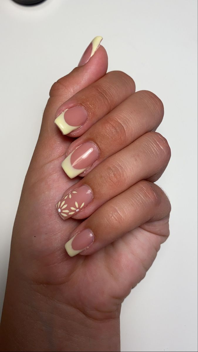 Chic Nude and Pastel Yellow French Tip Nail Design with Floral Accents.