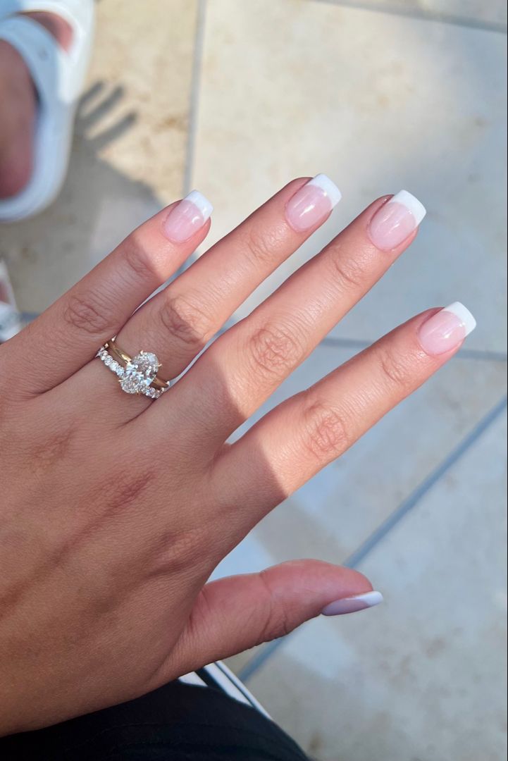 Timeless Elegance: Classic French Manicure Paired with a Glamorous Stacked Ring Set.