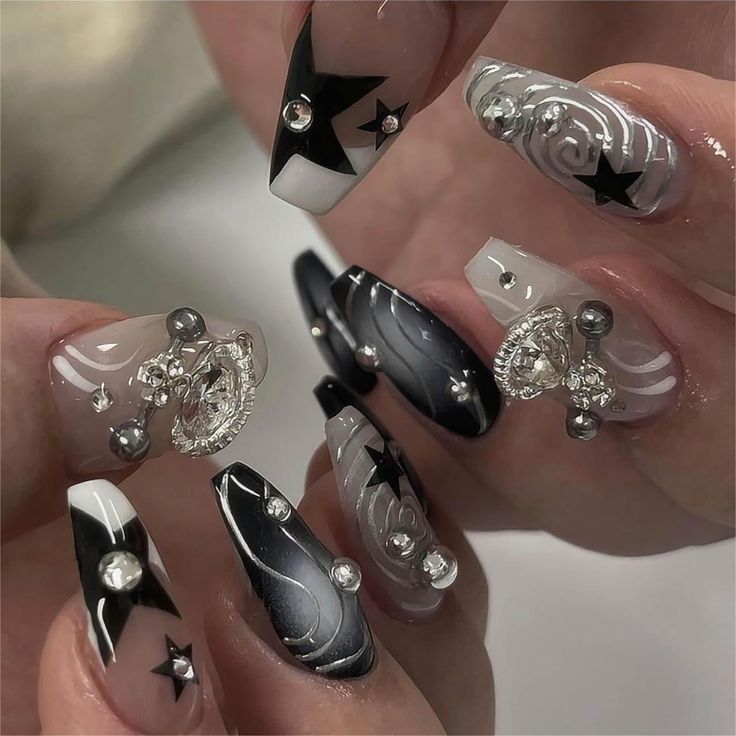 Chic Black and White Nail Design with Glamorous Rhinestones and Star Motifs.