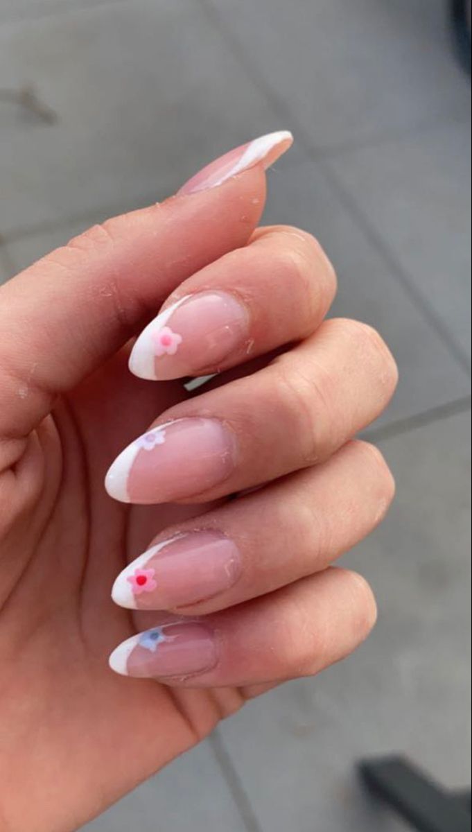 Chic French Tip Nails Adorned with Playful Pink Flower Accents.