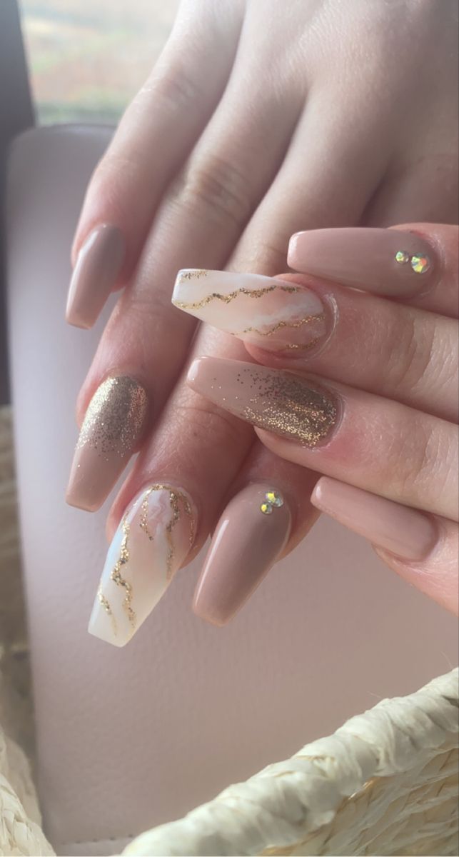 Elegant Tapered Square Nail Design with Soft Nude, Shimmering Gold Accents, and Gem Enhancements for Special Occasions.