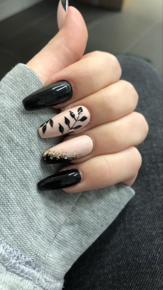 Chic Nail Design: Glossy Black and Soft Nude with Intricate Leaf Patterns and Subtle Glitter.