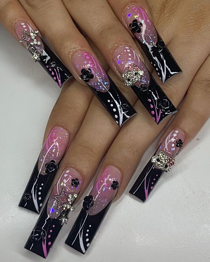 Vibrant Nail Design: Black Tips, Pink Accents, Floral Motifs, and Sparkly Embellishments.