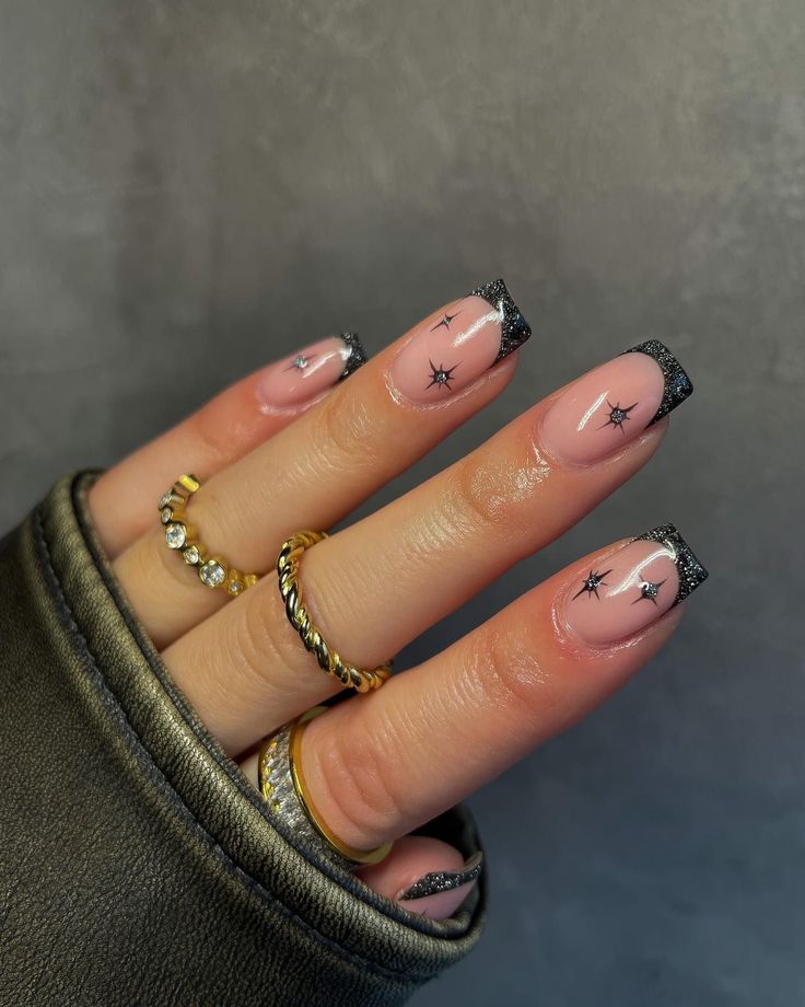 Elegant Chic Nail Design: Nude Base with Black Tips and Celestial Star Motifs.