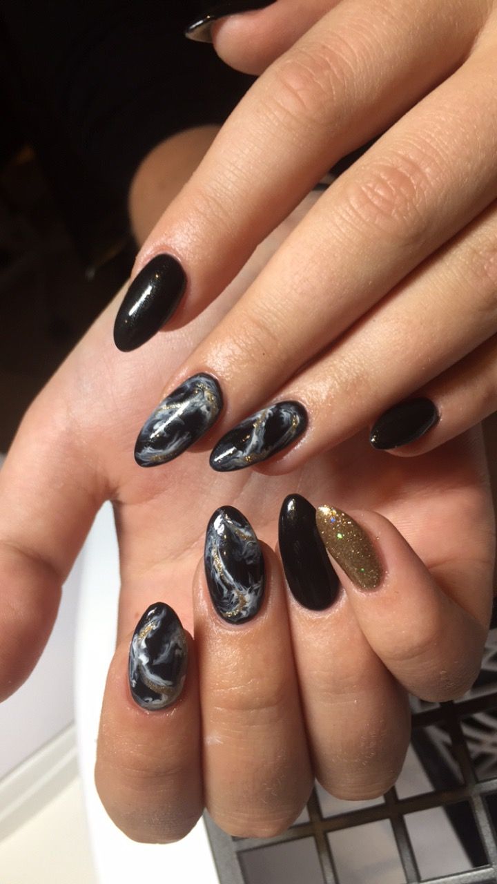 Chic Black and Gold Marble Nail Design with Glitter Accent.