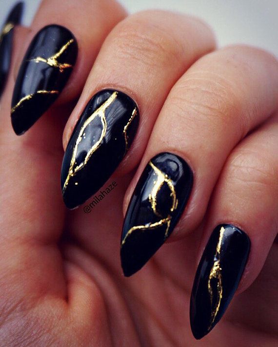 Sophisticated Black Nail Design with Striking Gold Foil Accents and Glossy Finish.