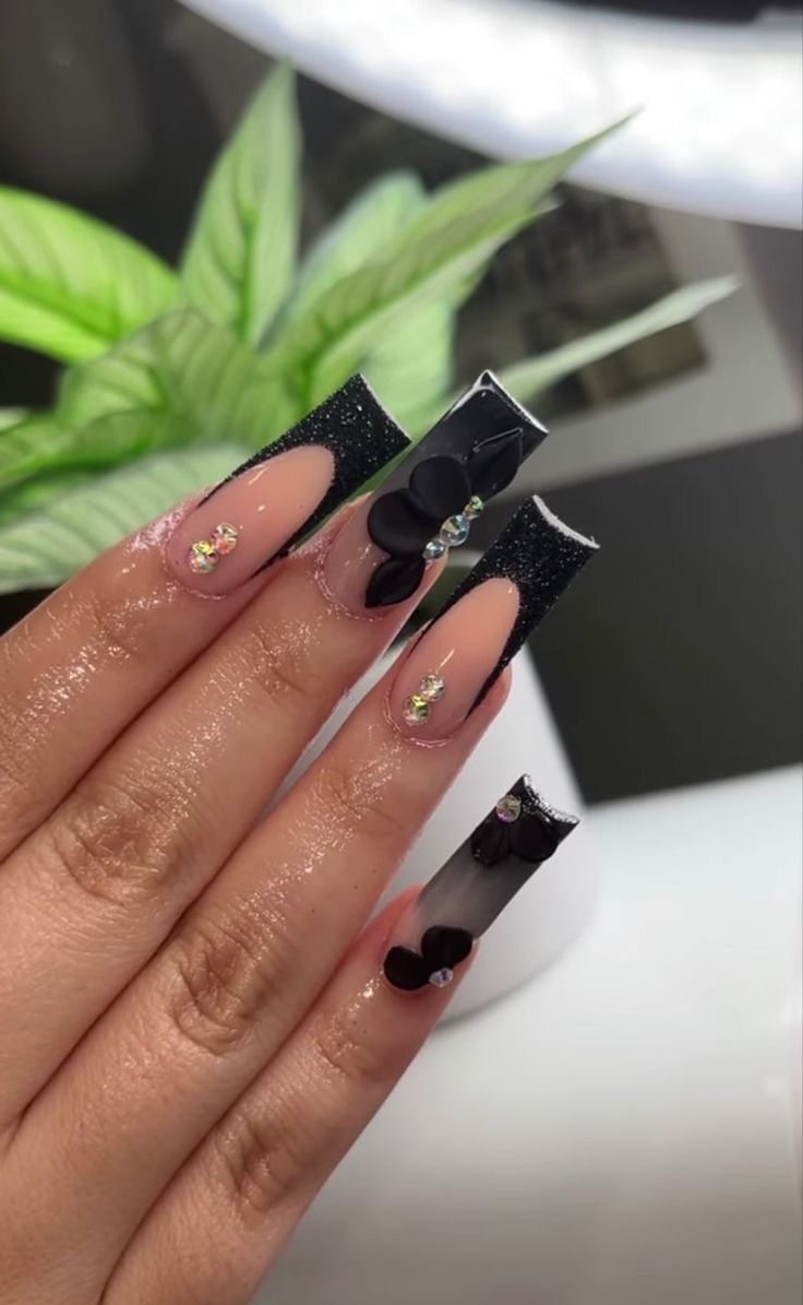 Glamorous Nail Design: Glossy Black and Nude with Floral Embellishments and Rhinestones