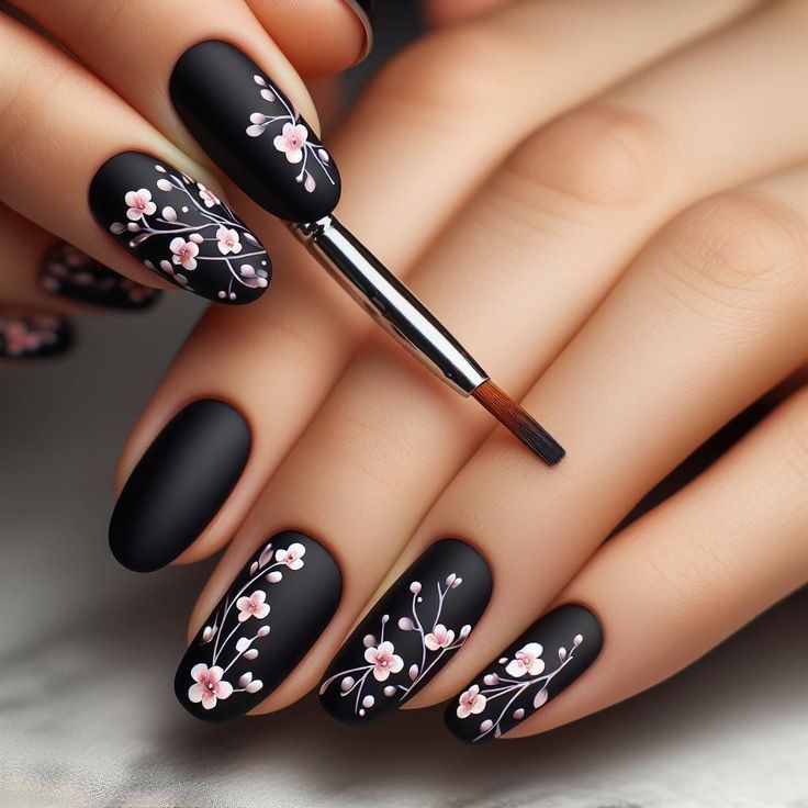 Sophisticated Matte Black Nails with Delicate Pink Floral Accents for Stylish Statement.