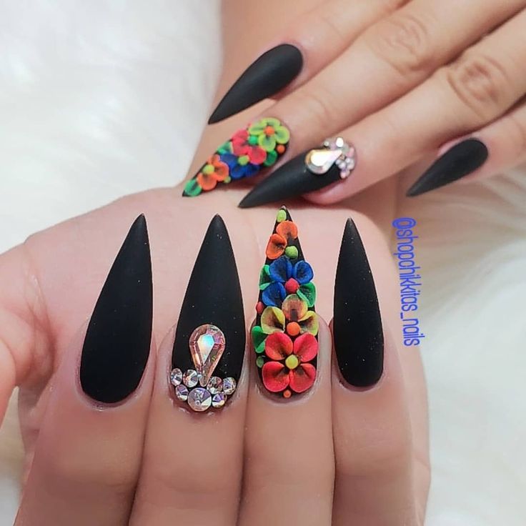 Bold Black Matte Nails Enhanced with Vibrant Floral and Gem Embellishments.