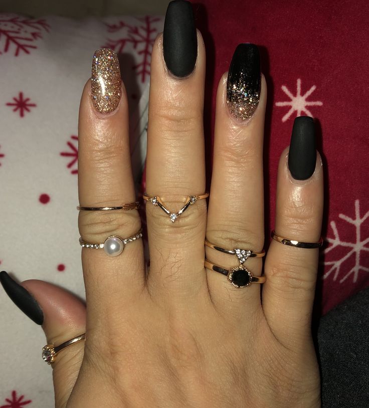 Sophisticated Matte Black and Gold Glitter Nail Design with Elegant Accessories.