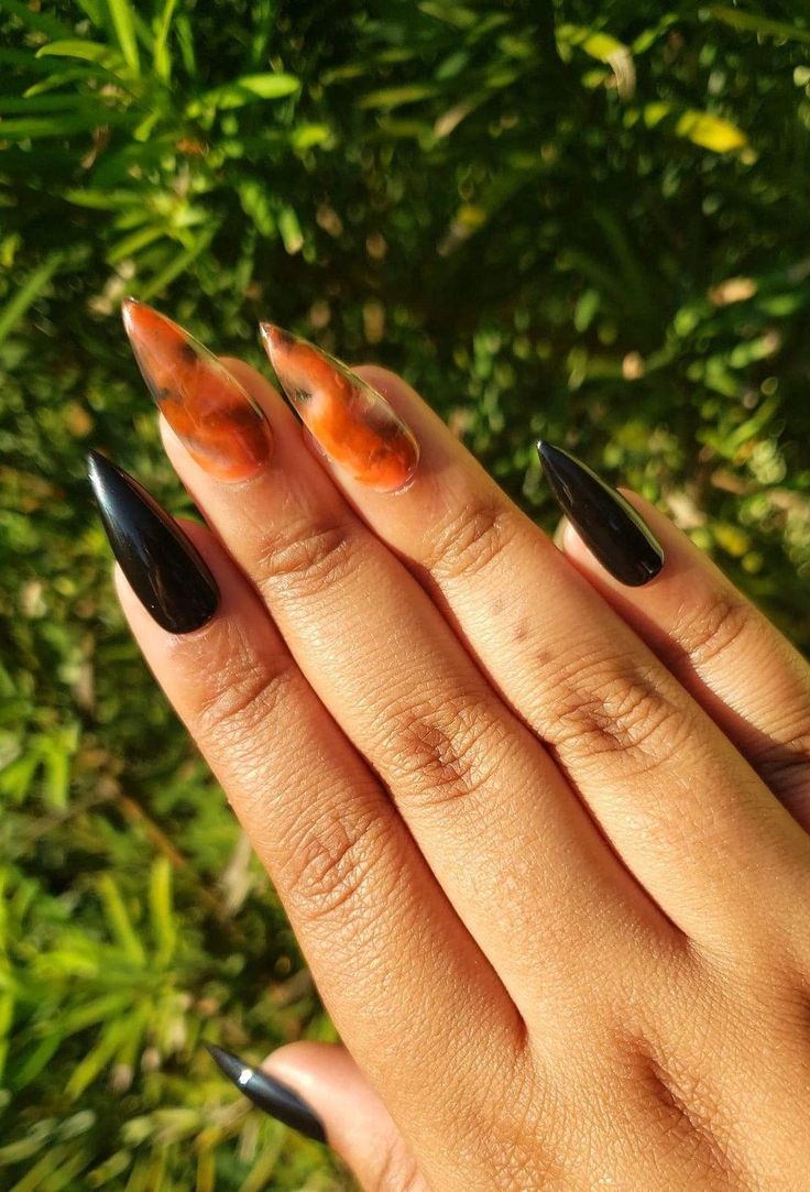 Bold Black and Vibrant Orange Nail Design with Artistic Marble Effects.