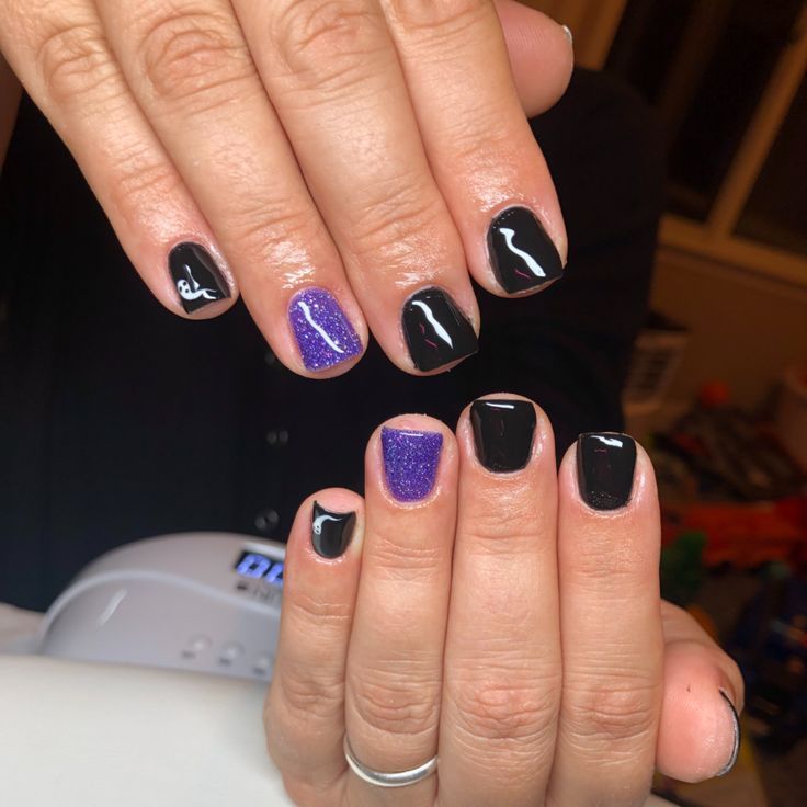 Bold Black Manicure with Sparkly Purple Accents and Delicate White Line Art