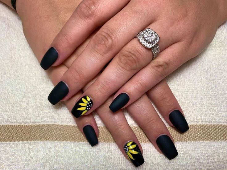 Elegant Matte Black Nails with Cheerful Yellow Floral Accents and Sparkling Rhinestones.