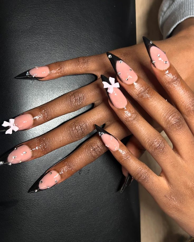 Chic Nude and Black Nail Design with Floral Accents and Sparkling Embellishments.