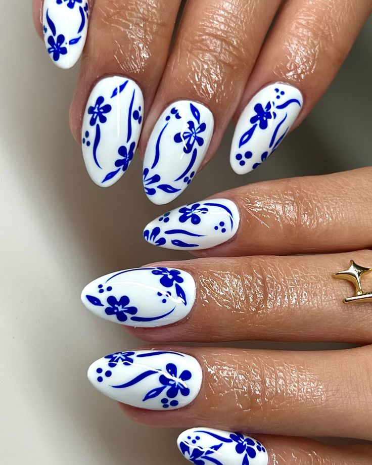 Elegant Floral Nail Design with Intricate Blue Patterns on Glossy White Background.