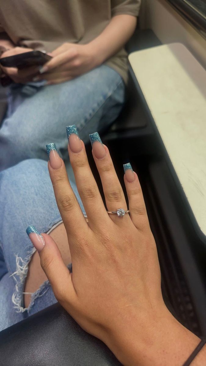 Sophisticated Nude and Shimmering Teal Nail Design with Sparkling Accents.