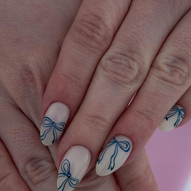 Chic Beige Nail Design with Elegant Blue Ribbon Motifs