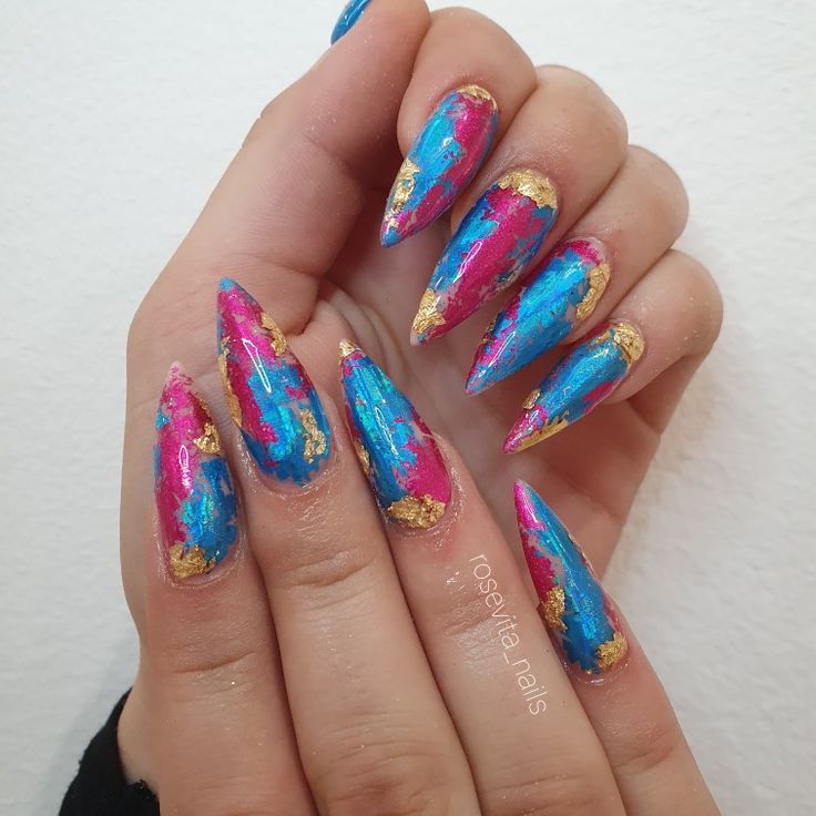 Dramatic Stiletto Nail Design with Pink, Blue, and Gold Embellishments.