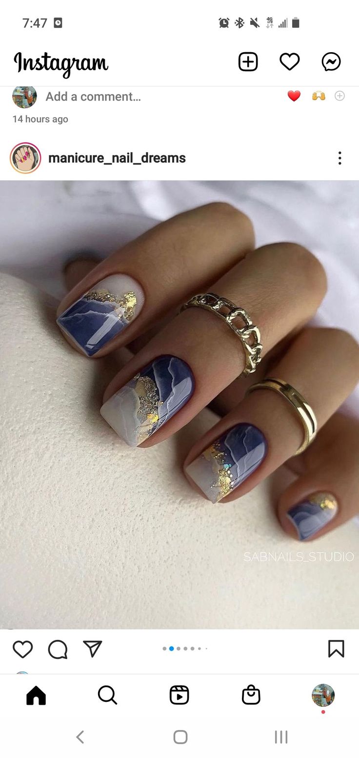 Artistic Blue and White Nail Design with Gold Accents and Stylish Ring Coordination.