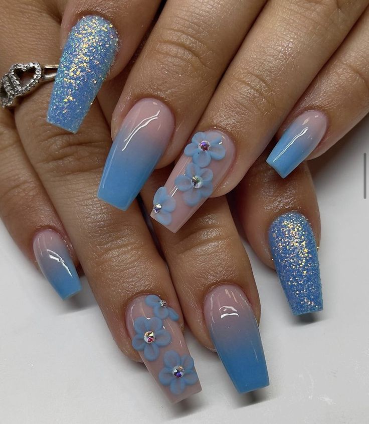 Elegant Gradient Blue Nail Design with Glitter and Floral Accents for a Fun Statement Look.