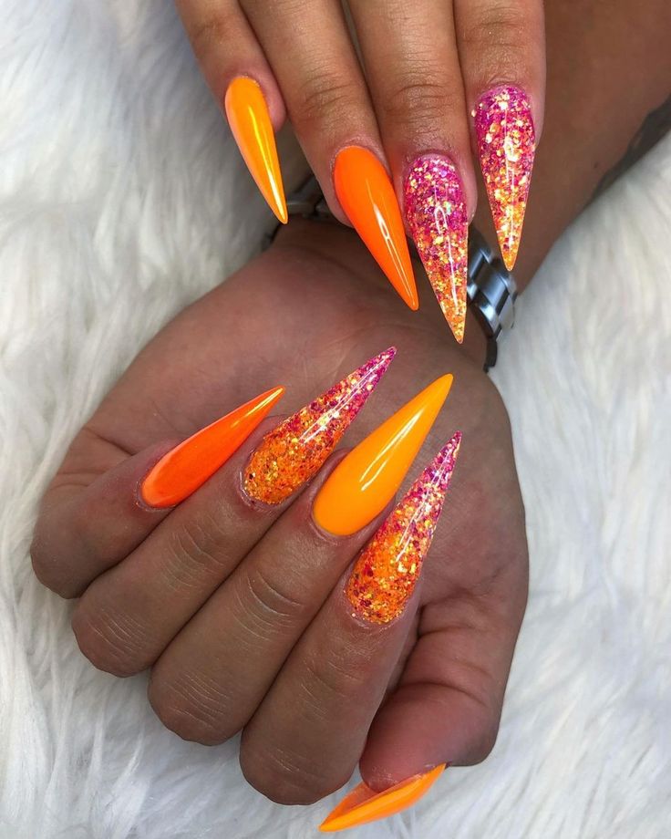 Bold Stiletto Nail Design: Bright Orange Shades with Glittery Orange-Pink Accents.