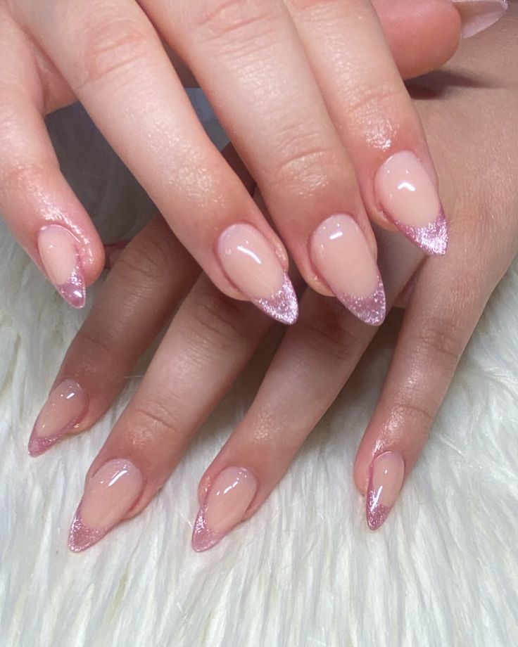 Elegant Ombre Stiletto Nails: Soft Pink Base with Glitter Tips for Glamorous Appeal.