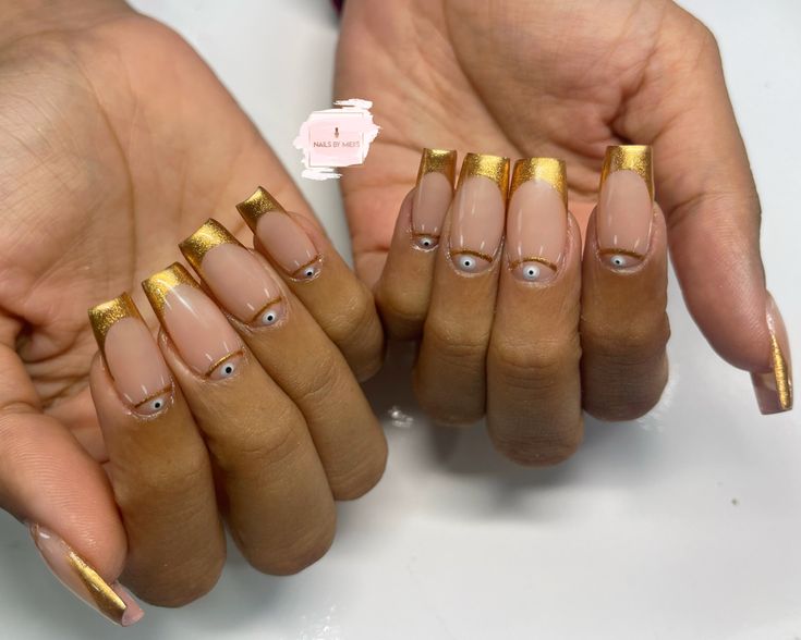 Elegant Gold-Tipped Nails with Eye Designs: A Glamorous Blend of Modern Trends and Playful Accents.