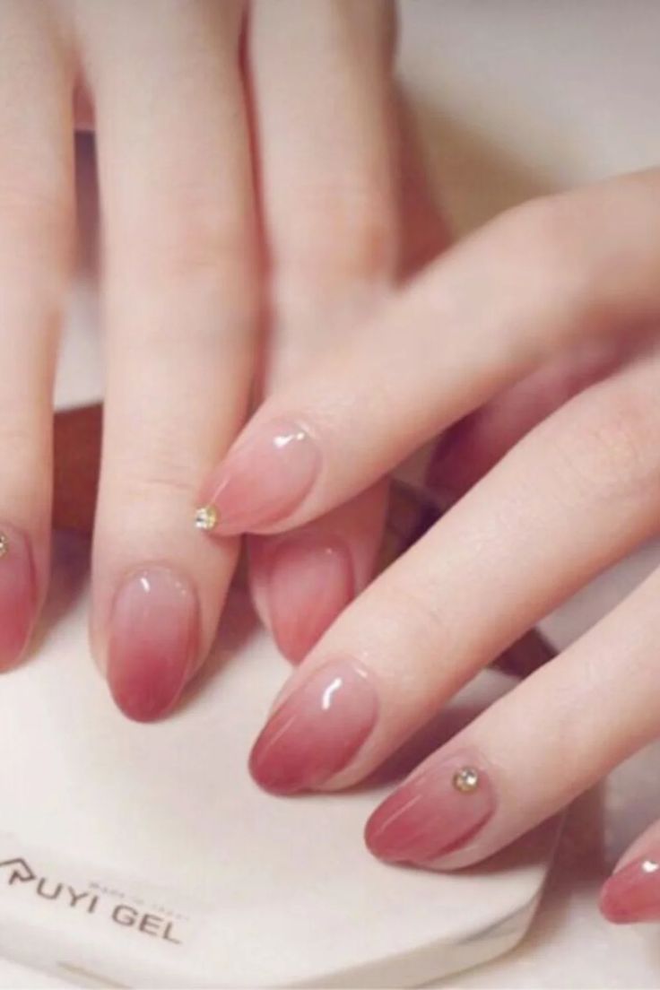 Sophisticated Ombre Nails: A Glamorous Gradient of Peach to Rose with Elegant Gem Accents.