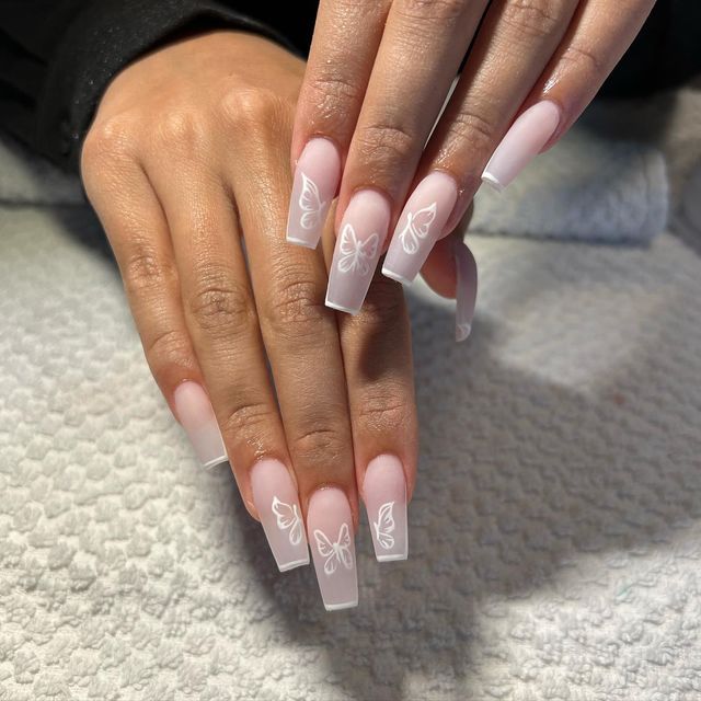 Elegant Soft Pink Nails with Delicate White Butterfly Designs for a Sophisticated Look.