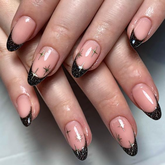 Chic Nude and Black Nail Design with Gold Star Accents and Glossy-Matte Finish.