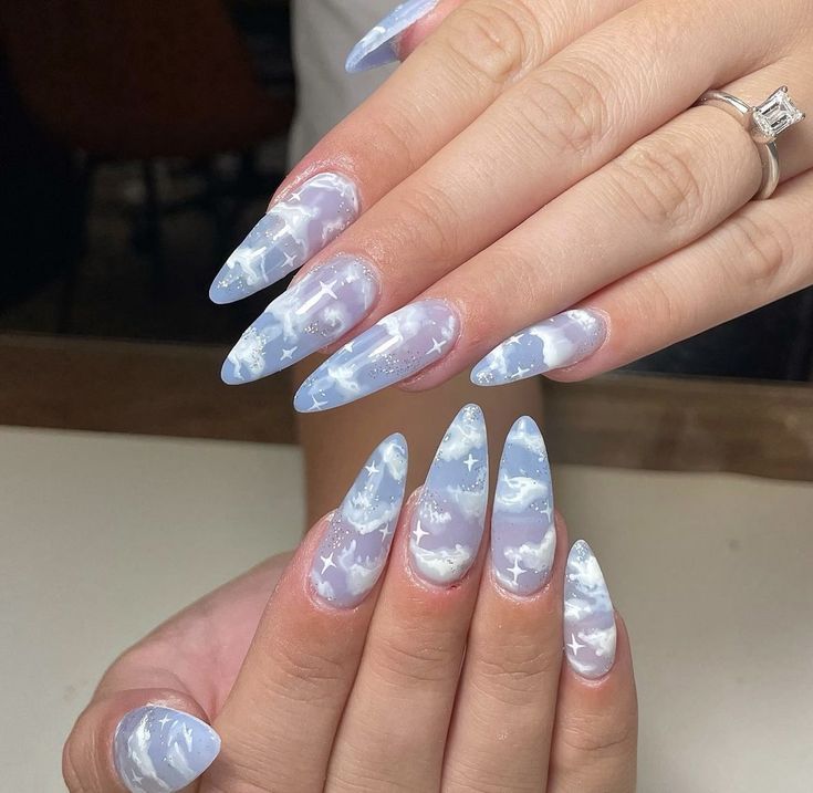 Elegant Dreamy Sky-Inspired Nail Design with Pastel Blue Background and Whimsical Cloud and Star Patterns.