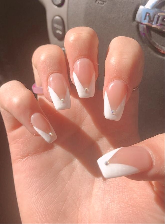 Chic Soft Pink and White Tip Nail Design with Elegant V-Shape and Gem Embellishments.