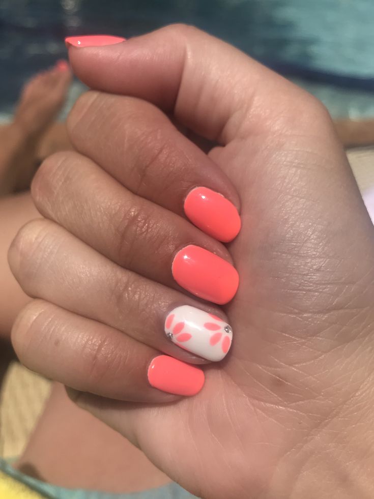 Vibrant Coral Nails with Floral Accents Perfect for Summer Vibes.