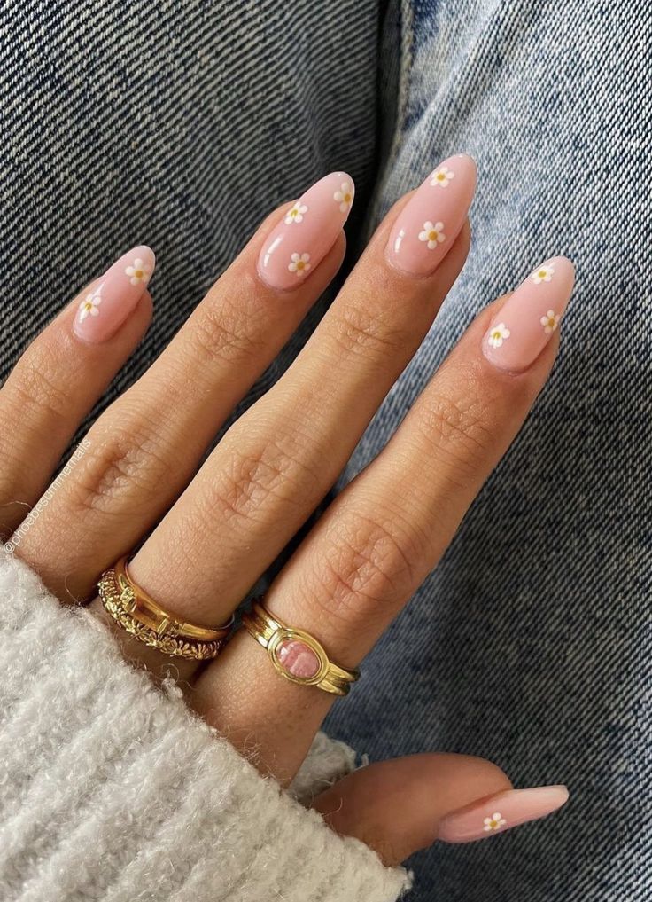 Elegant Pastel Pink Almond Nails Adorned with Floral Accents and Gold Rings