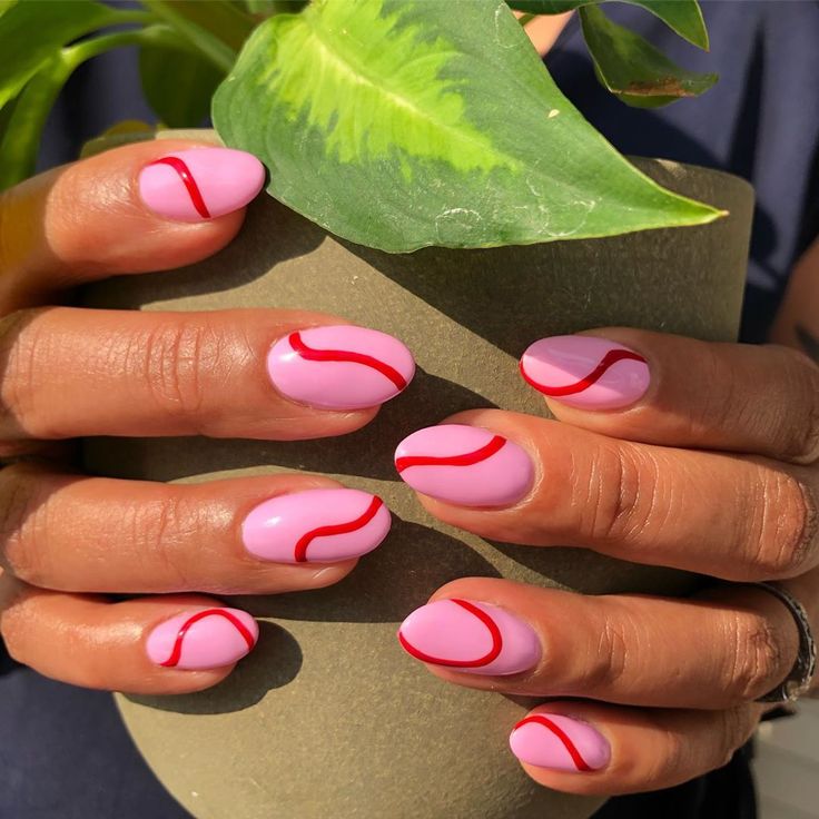 Vibrant Pastel Pink Nails with Playful Red Wavy Lines for Trendy Appeal.