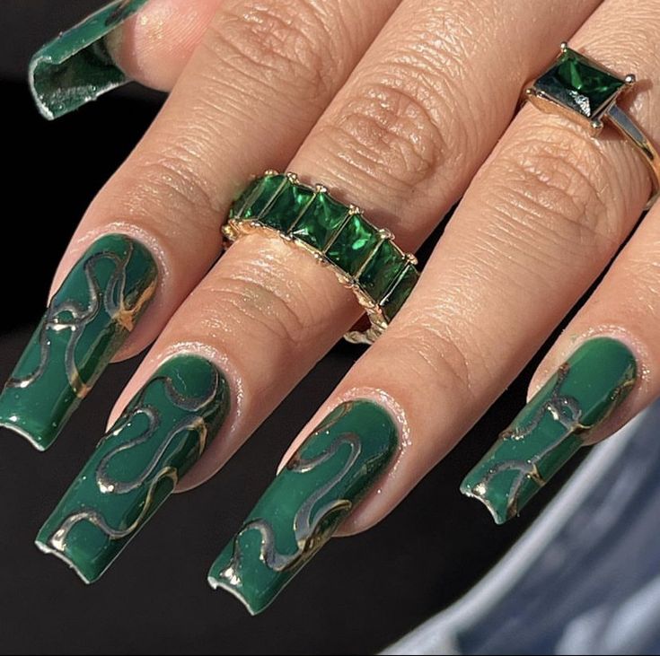 Luxurious Emerald Green Nail Design with Metallic Swirls and Complementary Rings.