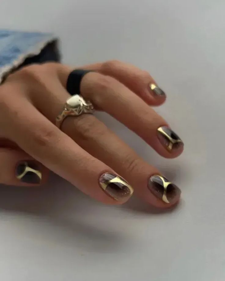 Chic Nail Design: Modern Dark Shades with Metallic Gold Accents and Geometric Patterns for a Bold Statement.