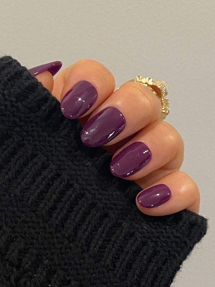 Chic Oval Purple Nails with Glossy Finish Complemented by a Cozy Black Sweater.