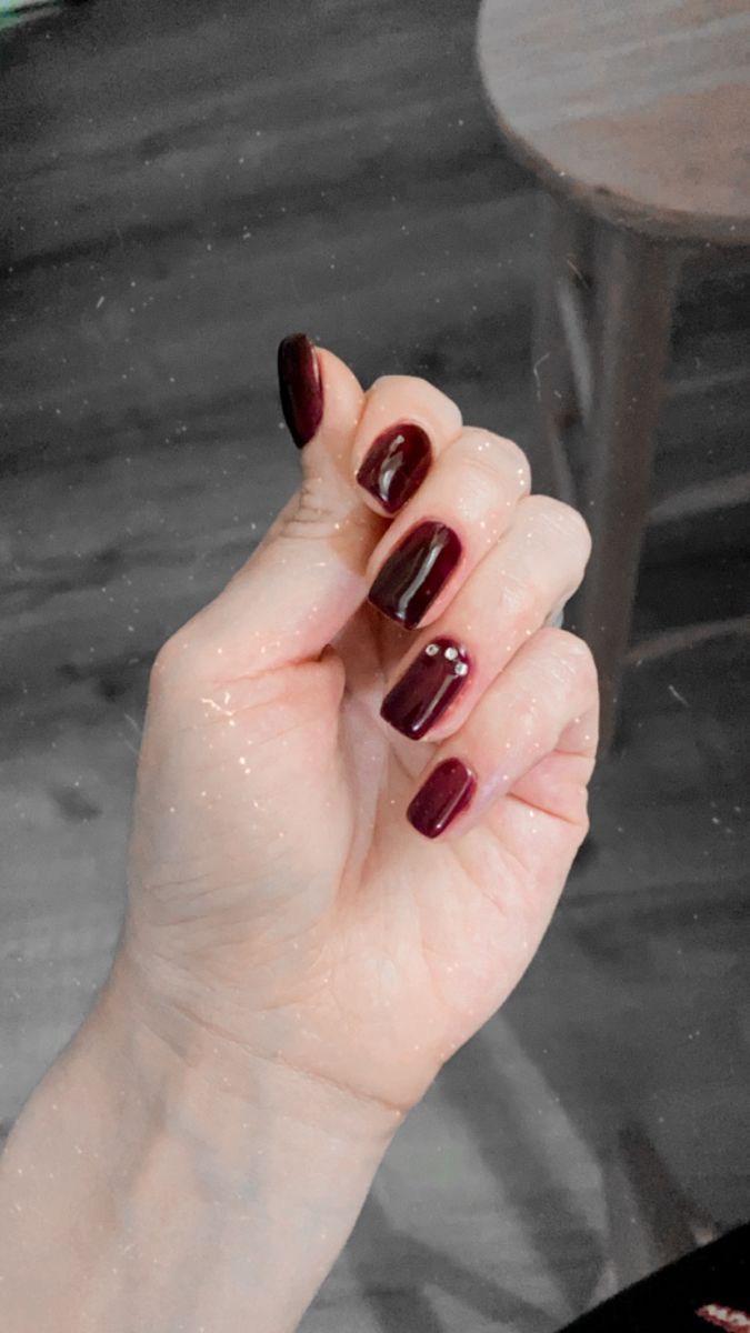 Sophisticated Burgundy Nails with Glossy Finish and Tasteful Embellishments.