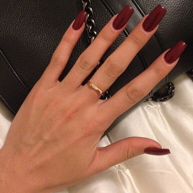 Sophisticated Almond-Shaped Nails with Deep Burgundy Polish and Chic Gold Ring Accent.