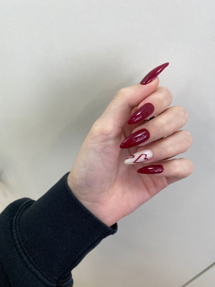 Sophisticated Burgundy Almond Nail Design with Charming Heart Accent and Glossy Finish.