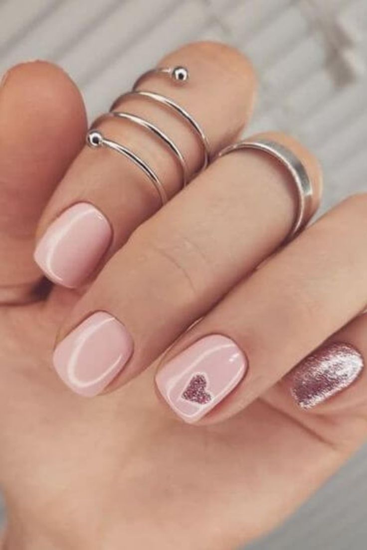 Chic Soft Pink Nail Design with Heart Accent and Glitter Detail.