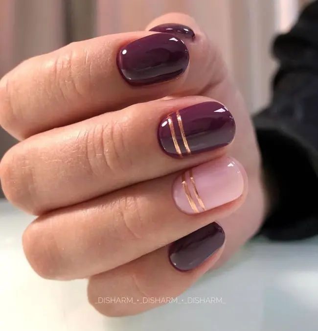 Sophisticated Deep Purple and Soft Pink Nail Design with Glamorous Gold Stripes.