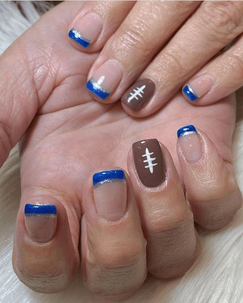 Playful Sporty Nail Design with Glittery Blue Tips and Football Motif for Team Spirit.