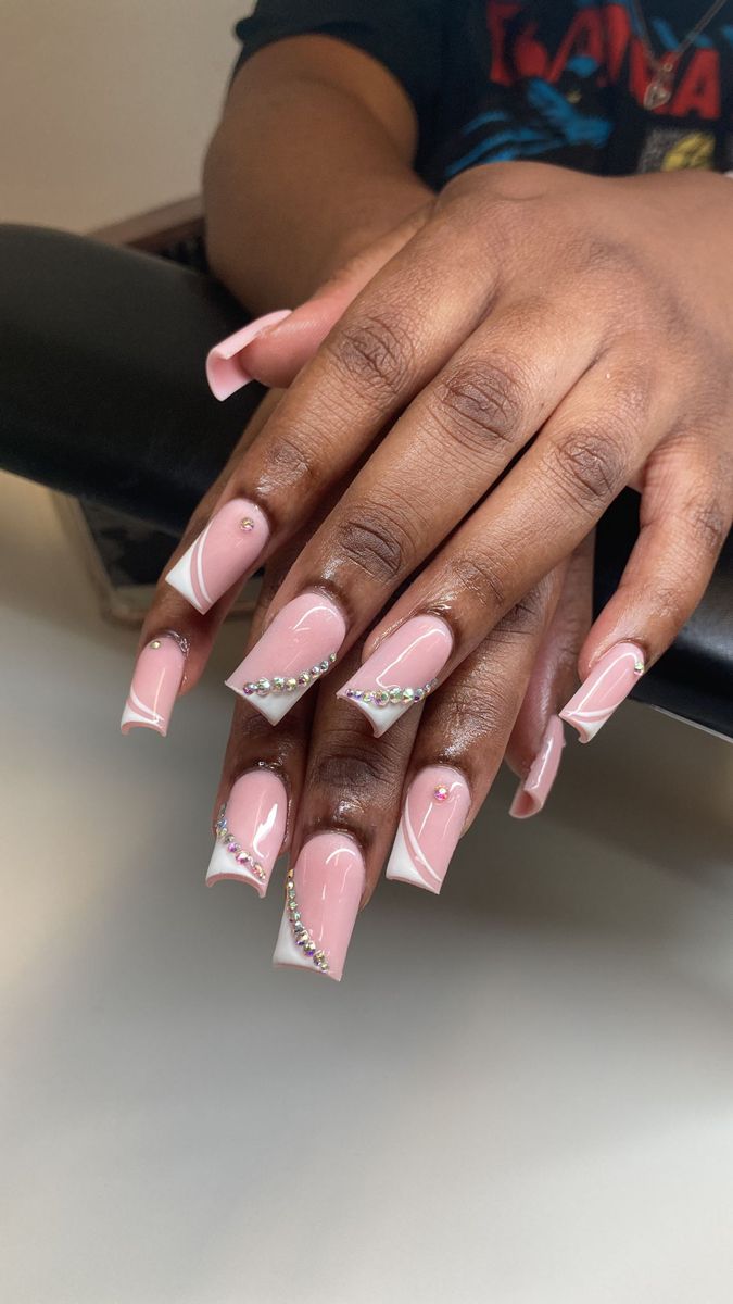 Sophisticated Soft Pink Nail Design with Intricate White Accents and Sparkling Rhinestones.