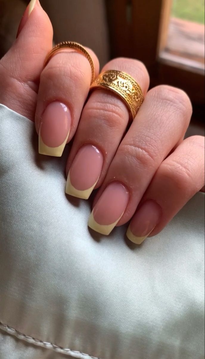 Elegant Soft Pink and White Tip Nail Design Accentuated by Delicate Gold Accessories.