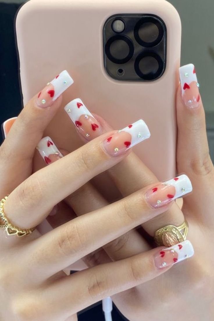 Playful Valentine's Nail Design with White Tips, Scattered Hearts, and Sparkling Rhinestones.