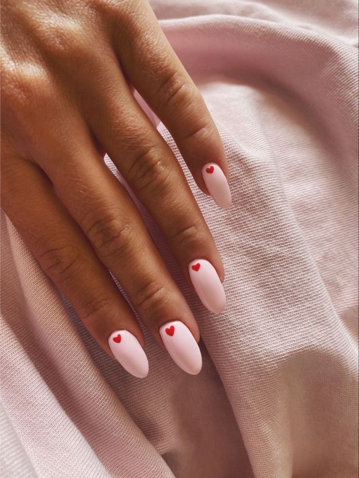 Romantic Pastel Pink Nails with Glossy Red Heart Accents for a Playful Aesthetic.