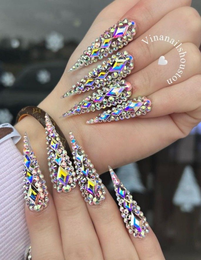 Glamorous Elongated Nail Design Adorned with Rhinestones and Colorful Embellishments.