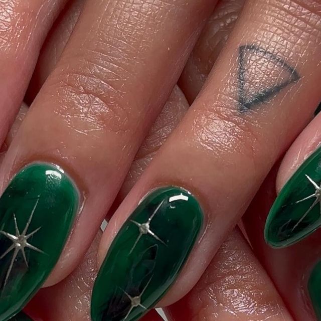 Captivating Emerald Green Nails with Silver Star Accents for a Bold Statement.